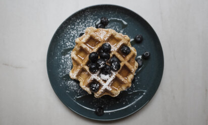 Draufsicht auf Waffeln mit Honig und Blaubeeren im Teller auf dem Tisch - CAVF62322