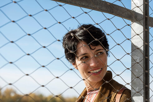 Smiling woman behind fence - CUF49282