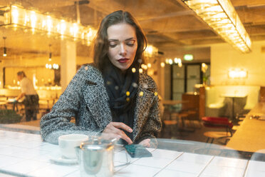 Junge Frau benutzt Smartphone in einem Café, London, UK - CUF49292