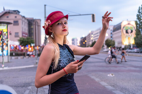 Hipster-Frau, die ein Taxi ruft, Berlin, Deutschland, lizenzfreies Stockfoto