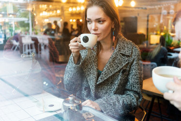 Junge Frau trinkt Kaffee mit einem Freund in einem Café, London, UK - CUF49363