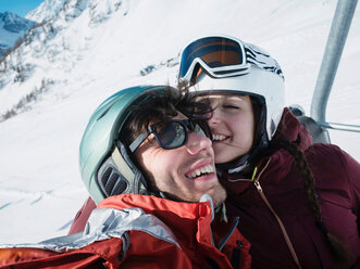 Skifahrendes Paar mit Helm und Skibrille im Skilift, Alpe Ciamporino, Piemont, Italien - CUF49412