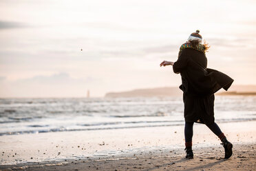 Frau wirft Kieselsteine am Strand - CUF49417