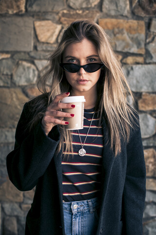 Porträt einer jungen Frau mit Sonnenbrille und Kaffee zum Mitnehmen, lizenzfreies Stockfoto