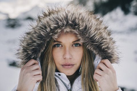 Porträt einer jungen blonden Frau mit Kapuze im Winter, lizenzfreies Stockfoto