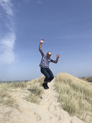 Belgien, Flandern, Nordseeküste, Mann springt in Dünen - GWF05904