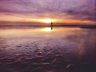 Belgium, Flanders, North Sea Coast, man walking along tide pool watching sunset and ocean waves, listening to the ocean sounds - GWF05912