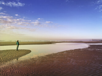 Belgien, Flandern, Nordsee, Küste, Frau steht am Strand im Abendlicht, entspannt sich und lauscht dem Meeresrauschen - GWF05915