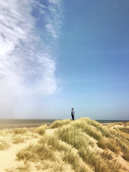 Belgien, Flandern, Nordsee, Küste, Mann steht in den Sanddünen, entspannt sich, beobachtet das Meer und lauscht den Meeresgeräuschen in der warmen Frühlingssonne - GWF05922