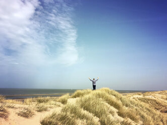 Belgien, Flandern, Nordsee, Küste, Mann entspannt sich in den Sanddünen, treibt Sport und beobachtet das Meer, lauscht den Meeresgeräuschen in der warmen Frühlingssonne - GWF05923