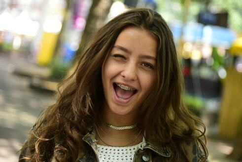 Portrait of winking teenage girl wearing braces - MIZF00798