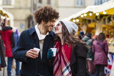 Happy affectionate young couple with hot drinks at Christmas market - MGIF00310
