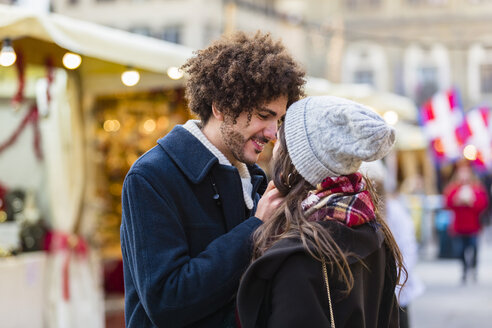 Glückliches, zärtliches junges Paar auf dem Weihnachtsmarkt - MGIF00312