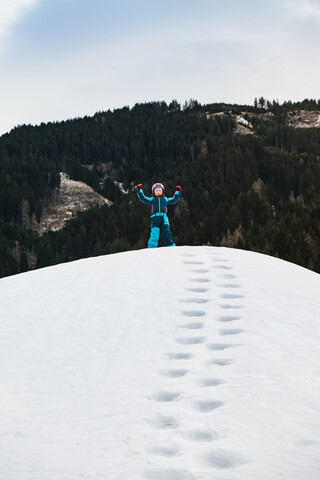 Italien, Trentino-Südtirol, glücklicher Junge auf einem Hügel im Winter, lizenzfreies Stockfoto