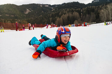 Italy, Trentino-Alto Adige, happy boy on tobogganing plastic sledge - MGIF00323