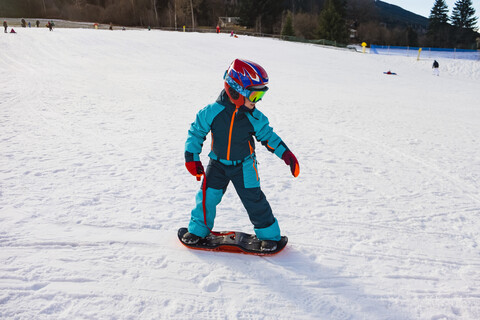 Italien, Trentino-Südtirol, Junge fährt auf kleinem Snowboard auf der Piste, lizenzfreies Stockfoto