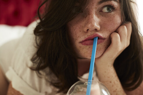 Portrait of bored teenage girl lying in bed with soft drink - AMEF00018