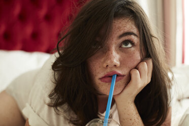 Porträt eines gelangweilten Teenagers, der mit einem Softdrink im Bett liegt - AMEF00019