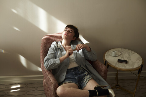 Teenage girl sitting in armchair looking away stock photo