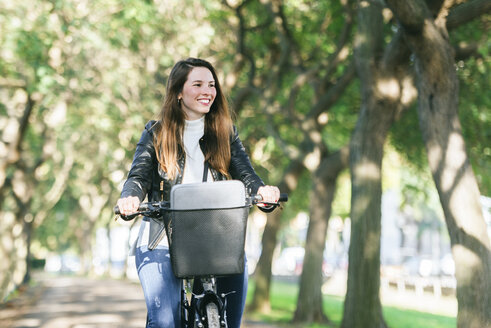 Lächelnde junge Frau beim Fahrradfahren im Park - KIJF02376