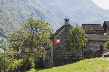 Schweiz, Tessin, Verzascatal, typisches Steinhaus mit Schweizer Nationalflagge - GWF05948