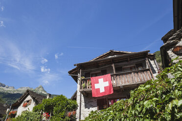 Schweiz, Tessin, Sonogno, typisches historisches Steinhaus mit Schweizer Fahne - GWF05976
