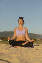 Woman meditating on the beach in the evening - KBF00535