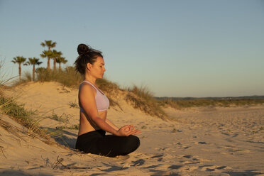 Woman meditating on the beach in the evening - KBF00538