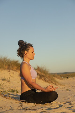 Meditierende Frau am Strand am Abend, lizenzfreies Stockfoto