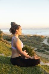 Woman meditating on the beach in the evening - KBF00542