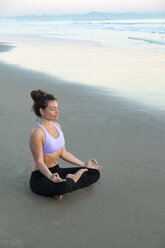 Woman meditating on the beach in the evening - KBF00545