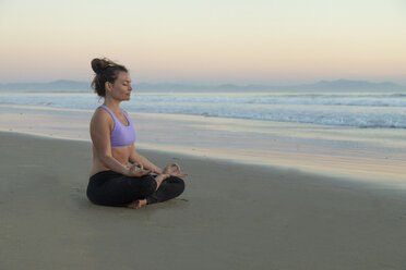 Woman meditating on the beach in the evening - KBF00546