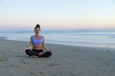 Woman meditating on the beach in the evening - KBF00547