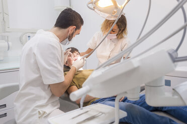 Assistant helping dentist in operating patient at medical clinic - CAVF62390