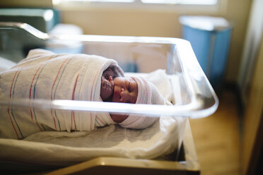 High angle view of cute newborn baby boy sleeping in hospital bassinet - CAVF62508