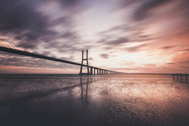 Silhouette Vasco Da Gama Brücke über den Fluss Tejo gegen bewölkten Himmel bei Sonnenaufgang - CAVF62529