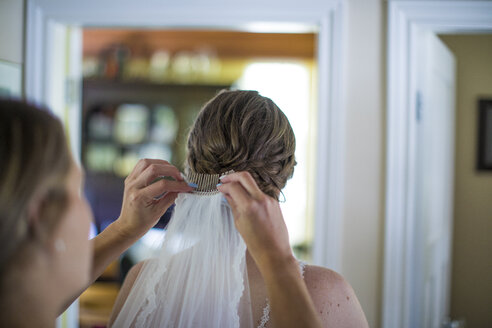 Ausgeschnittenes Bild einer Frau, die zu Hause einen Schleier vor der Braut trägt - CAVF62598