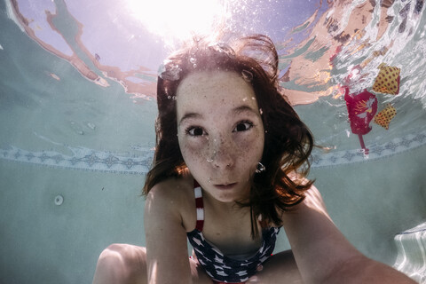 Porträt eines Mädchens, das beim Schwimmen im Schwimmbad in der Sonne ein Gesicht macht, lizenzfreies Stockfoto