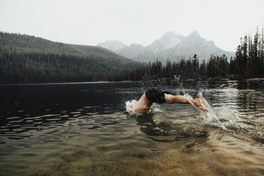 Shirtless man diving in lake against clear sky at forest - CAVF62620