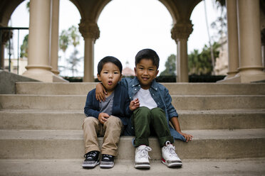 Portrait of cute brothers sitting on steps against sky in Balboa Park - CAVF62643