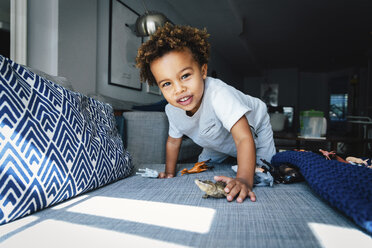 Porträt eines süßen Jungen, der zu Hause auf dem Sofa mit Spielzeug spielt - CAVF62671