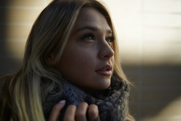 Close-up of thoughtful woman with blond hair wearing scarf while standing outdoors - CAVF62698