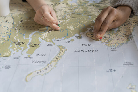 Freunde setzen Stecknadeln auf eine Landkarte, planen ihren Urlaub, Nahaufnahme, lizenzfreies Stockfoto