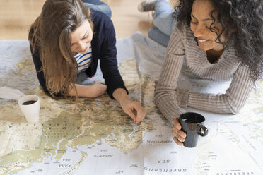Freunde setzen Stecknadeln auf eine Landkarte und planen ihren Urlaub - FMOF00425