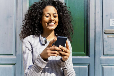 Lachende Frau mit Smartphone in der Hand - FMOF00439