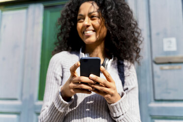 Lachende Frau mit Smartphone in der Hand - FMOF00440