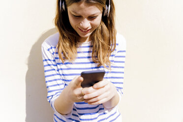 Junge Frau mit Kopfhörern und Smartphone - FMOF00448