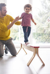 Father helping his daughter to balance on a beam - JOSF03083