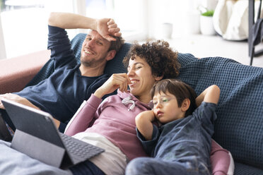 Familie liegt auf der Couch und schaut einen Film auf ihrem Tablet - JOSF03092