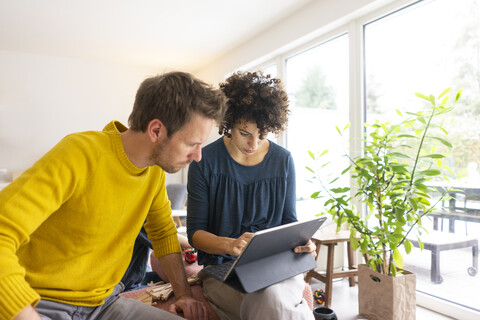 Couple sitting in living room, using digital tablet stock photo